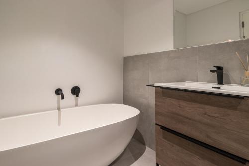 een badkamer met een wit bad en een wastafel bij Luxury Escape at Alphen Glen Constantia in Kaapstad