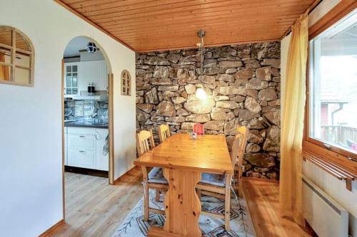 a dining room with a wooden table and a stone wall at Minnebo stuga in Hässleholm