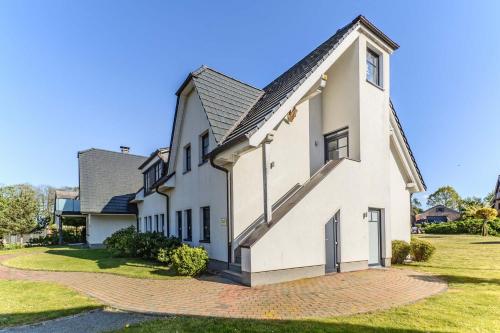 ein weißes Haus mit einem Walmdach in der Unterkunft Mönchgut - Strand Resort Rex Rugia App 05 in Lobbe