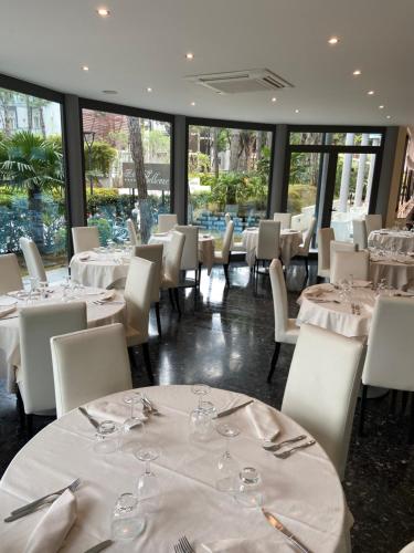 a dining room with white tables and white chairs at Hotel Bellevue in Lignano Sabbiadoro