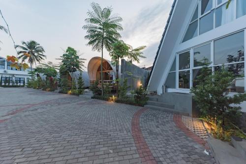 a building with a palm tree in front of it at Urbanview Hotel Khayrizsan Tasikmalaya by RedDoorz in Tasikmalaya