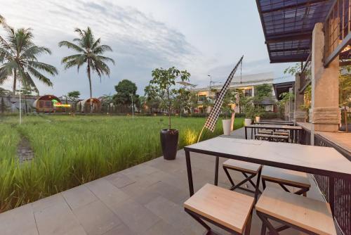 a patio with tables and chairs in front of a field at Urbanview Hotel Khayrizsan Tasikmalaya by RedDoorz in Tasikmalaya