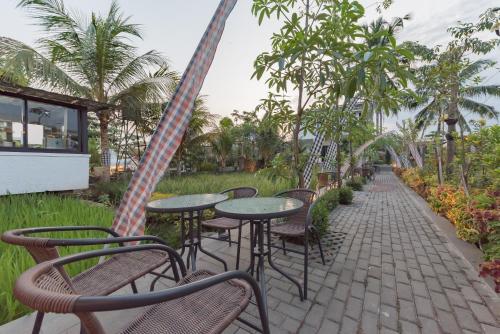 a patio with tables and chairs and palm trees at Urbanview Hotel Khayrizsan Tasikmalaya by RedDoorz in Tasikmalaya
