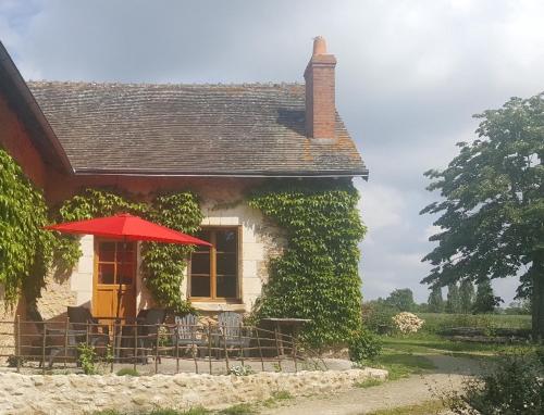 uma casa com uma mesa e um guarda-chuva vermelho em LE GÎTE DU VIGNERON em Sennevières
