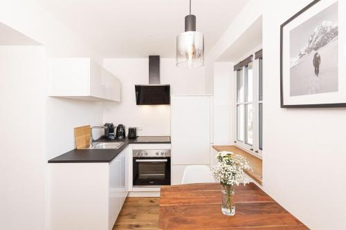 uma cozinha com paredes brancas e uma mesa com flores em Apartment - Lärchenhof em Mauterndorf