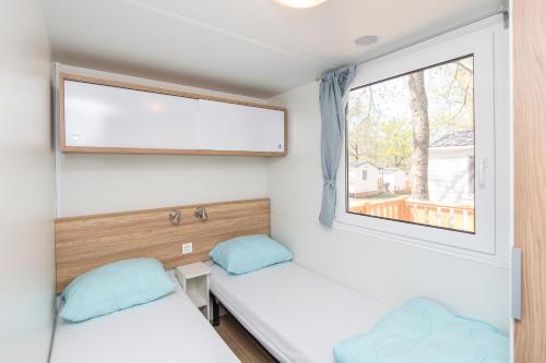 two beds in a small room with a window at Albatross Mobile Homes on Camping Baia Verde in Manerba del Garda