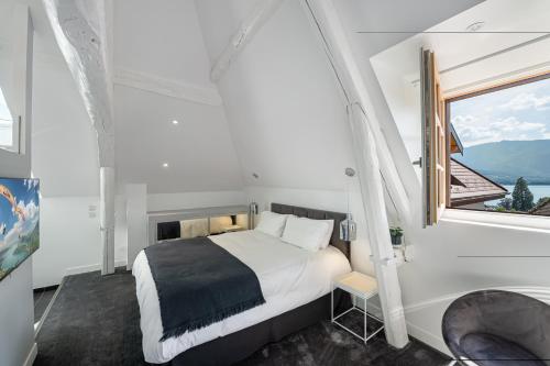 ein Schlafzimmer mit einem Bett und einem großen Fenster in der Unterkunft Le Chicissime, coeur du village, LLA Selections by Location lac Annecy in Talloires