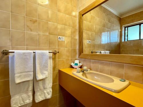 a bathroom with a sink and a mirror and towels at Ocean View Motor Inn Merimbula in Merimbula