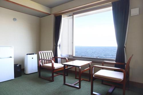 a room with a table and chairs and a large window at Ooedo Onsen Monogatari Beppu Seifu in Beppu