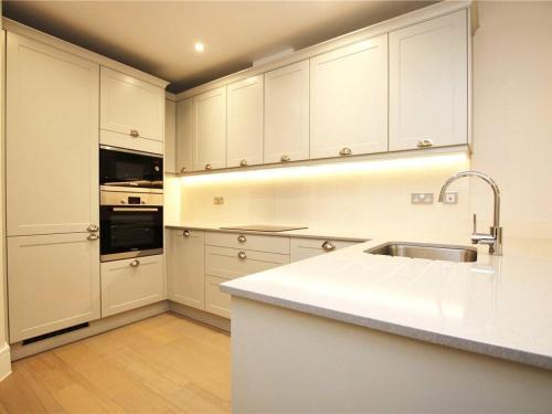 a kitchen with white cabinets and a sink at Lakeside LUX bedroom with parking, M4 Jct 11, next to train station in Reading