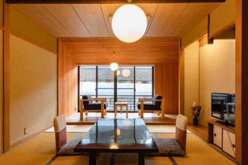 a dining room with a table and chairs and a television at TSUCHIYA Kinosaki onsen in Toyooka