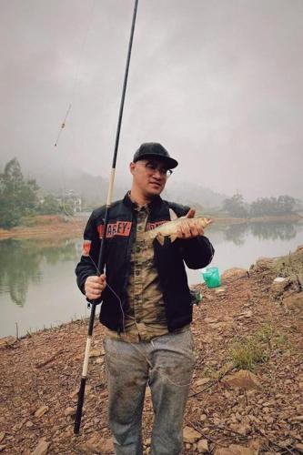 a man holding a fish with a fishing pole at Nhà trên cây in Hanoi