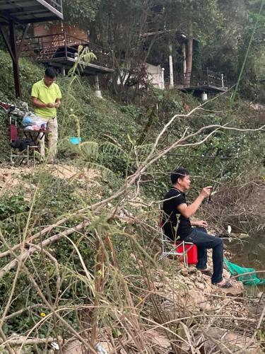two men sitting in chairs in the grass at Nhà trên cây in Hanoi