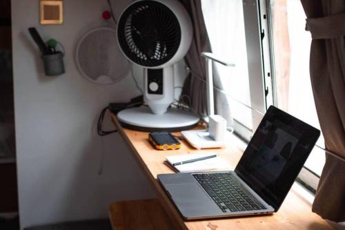 a laptop computer sitting on a desk with a fan at Baan Bus 81/11 Krabi in Ao Nang Beach