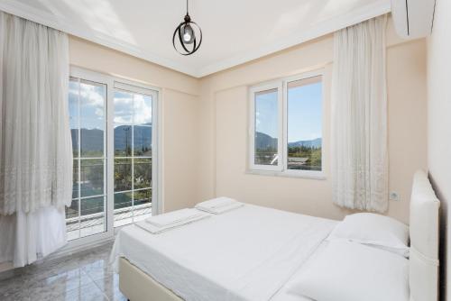 a white bedroom with two beds and windows at Villa Corals in Dalyan