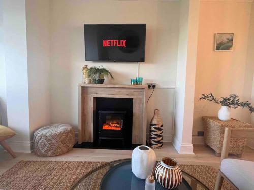 a living room with a fireplace with a tv above it at Amazing sea views and hot tub in Amble