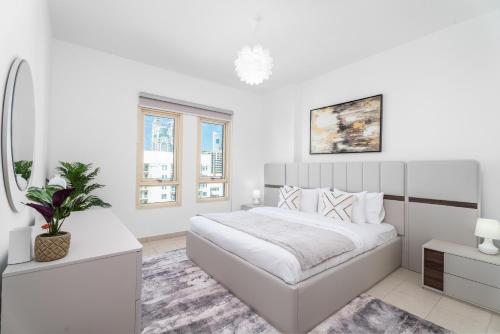a white bedroom with a large bed and a window at EasyGo - Al Samar 4 - 2 Bedroom & Maid in Dubai