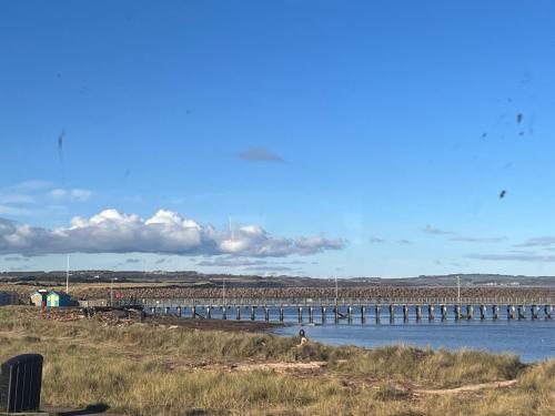 a long bridge over a body of water at Amazing sea views and hot tub in Amble