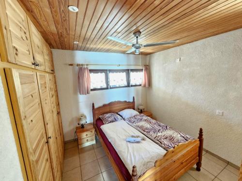 une chambre avec un lit avec un plafond en bois dans l'établissement Maison Le Guetali, à Zonza
