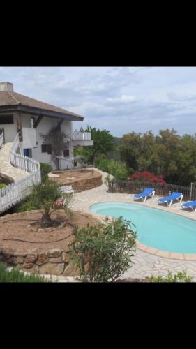 une piscine avec deux chaises bleues à côté d'une maison dans l'établissement Maison Le Guetali, à Zonza