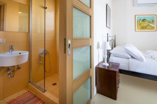 a bathroom with a shower and a sink and a bed at Villa Pasiphae in Stalos
