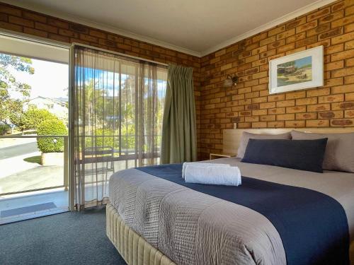 a bedroom with a large bed and a balcony at Ocean View Motor Inn Merimbula in Merimbula