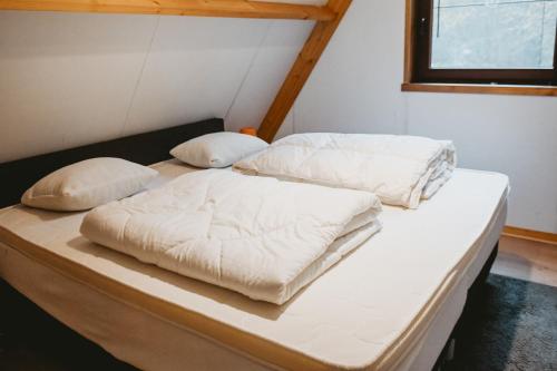 2 bedden in een kamer met witte lakens en kussens bij Boshuisje Rekem - Flora in Lanaken