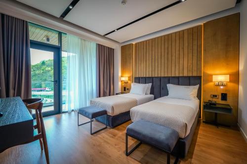 a hotel room with two beds and a window at Hotel Uji Ftohte Tepelene in Tepelenë