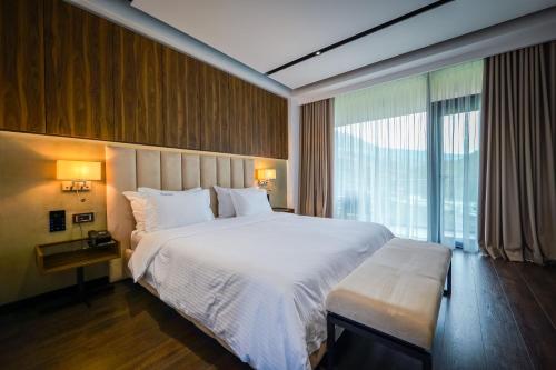 a bedroom with a large bed and a large window at Hotel Uji Ftohte Tepelene in Tepelenë