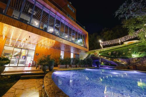 a swimming pool in front of a building at night at Hotel Uji Ftohte Tepelene in Tepelenë