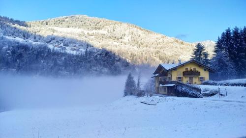 a house in the snow in front of a mountain at Eco-Baita Natura Spensierata in Canale San Bovo