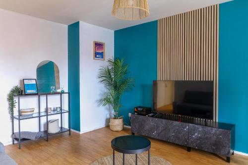 sala de estar con paredes azules y TV de pantalla plana. en Cocon Urbain à 2 pas de la Gare, en Nantes