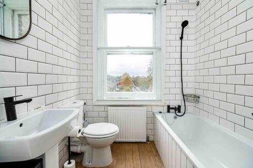 Baño blanco con aseo y lavamanos en Cosy 2 Bed Flat In East London en Londres