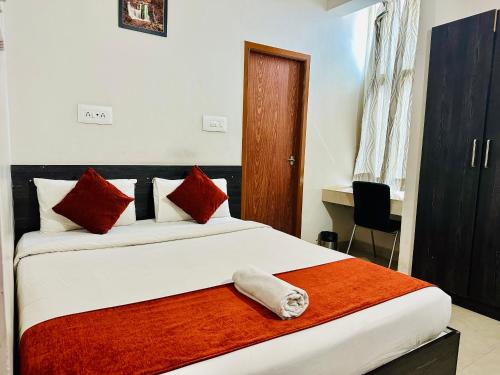 a bedroom with a large bed with red and white pillows at Orange Corner Hotel, MONTHLY STAY AVAILABLE in Yelahanka