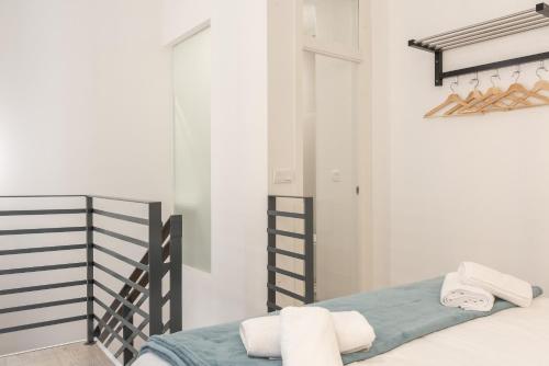 1 dormitorio con paredes blancas y 1 cama con toallas en Acanthus, en Sevilla