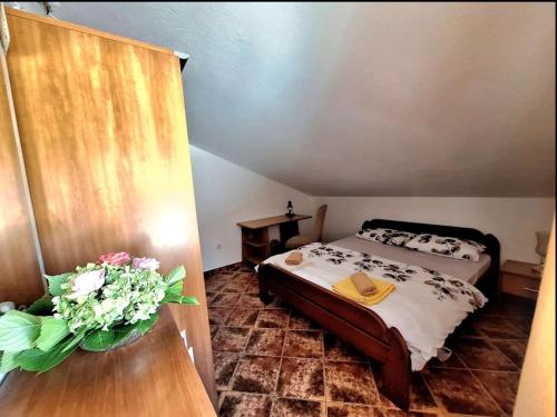 a bedroom with a bed and a vase of flowers on a table at Rose Apartment in Kotor