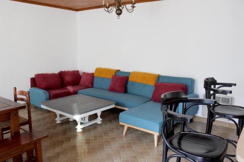 un salon avec un canapé bleu, des tables et des chaises dans l'établissement LES MIGLOU - Maison picarde entre Paris et la Champagne !, à Nogentel