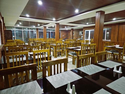 an empty restaurant with wooden tables and chairs at Tulips Village Resorts in Ooty