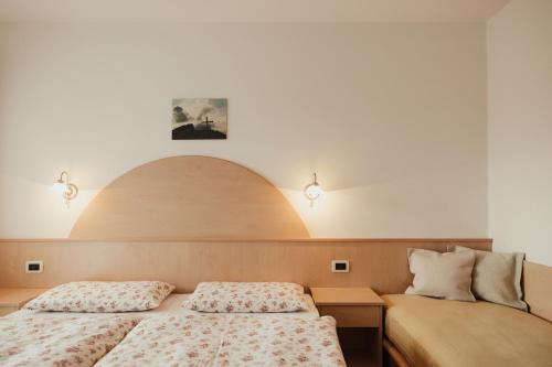 two beds in a room with two lamps on the wall at Residence Costa Burjada in Colfosco