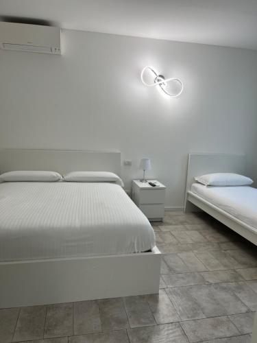 a white bedroom with two beds and a lamp at Seriana in Orio al Serio