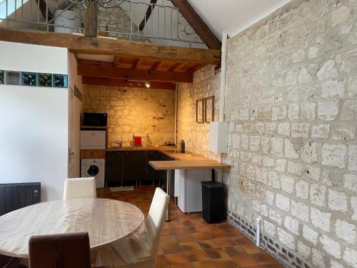 une cuisine avec une table et un mur en briques dans l'établissement la pierre de sainte catherine, à Sainte-Catherine