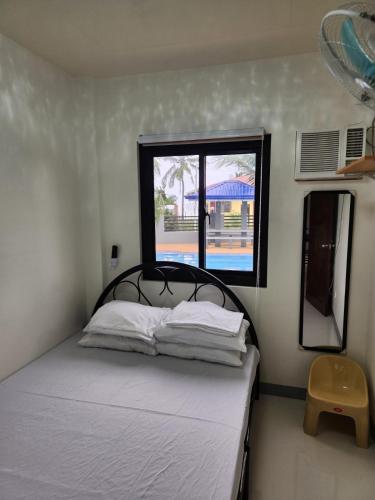 a small bedroom with a bed with a window at Triple J Villa Puerto Galera in Puerto Galera