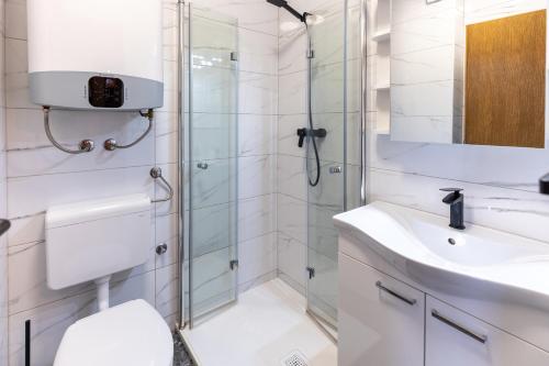 een witte badkamer met een douche en een wastafel bij Apartment Alpinea in Bohinj