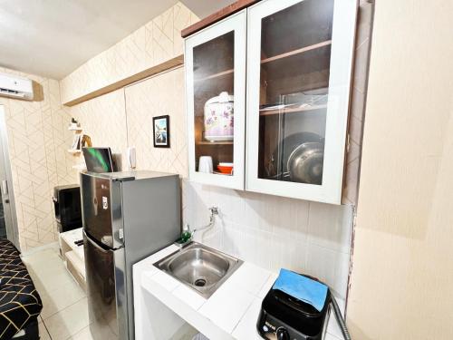 a small kitchen with a sink and a refrigerator at Cozy Studio 1BR at Green Bay Pluit Apartment in Jakarta