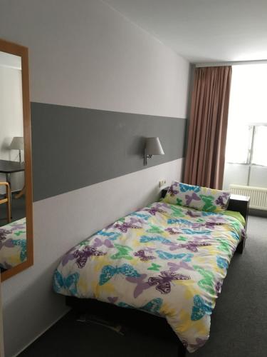 a bedroom with a bed with a colorful comforter at Business apartment in 3 star hotel Daimler Nah in Sindelfingen