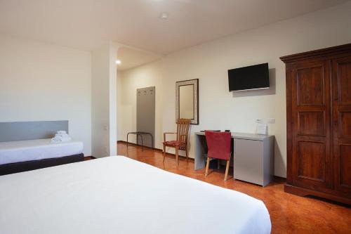 a bedroom with a bed and a desk with a tv at CDH Hotel Modena in Modena