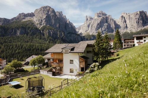 a house on a hill with mountains in the background at Residence Costa Burjada in Colfosco