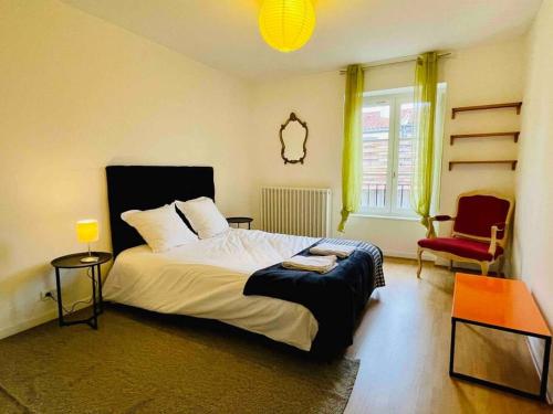 une chambre avec un lit et une chaise rouge dans l'établissement Hypercentre Clermont-FD terrasse + parking, à Clermont-Ferrand