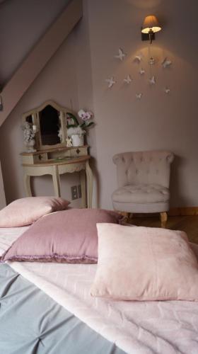 a bedroom with a bed with pink sheets and a chair at L'Ancienne Cure in Besain