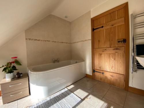 een badkamer met een ligbad en een houten deur bij Mallards Barn on a rural farm in Dingestow